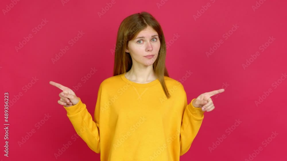 Young woman pointing to the laterals having doubts over isolated background Young woman pointing to the laterals having doubts over isolated background