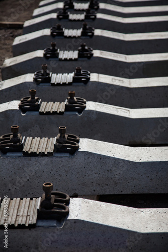 Concrete sleepers with metal bolts and furniture and rubber. Close-up photo, low depth-of-field. Second sleeper in focus only. Manufacturing plant.