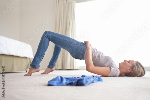 Theyre just too small. A young woman struggling to pull on her jeans.