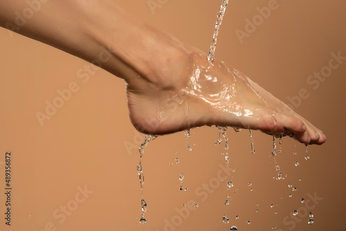 Canvas Close up of a female wet foot with water gliding over it on a beige background