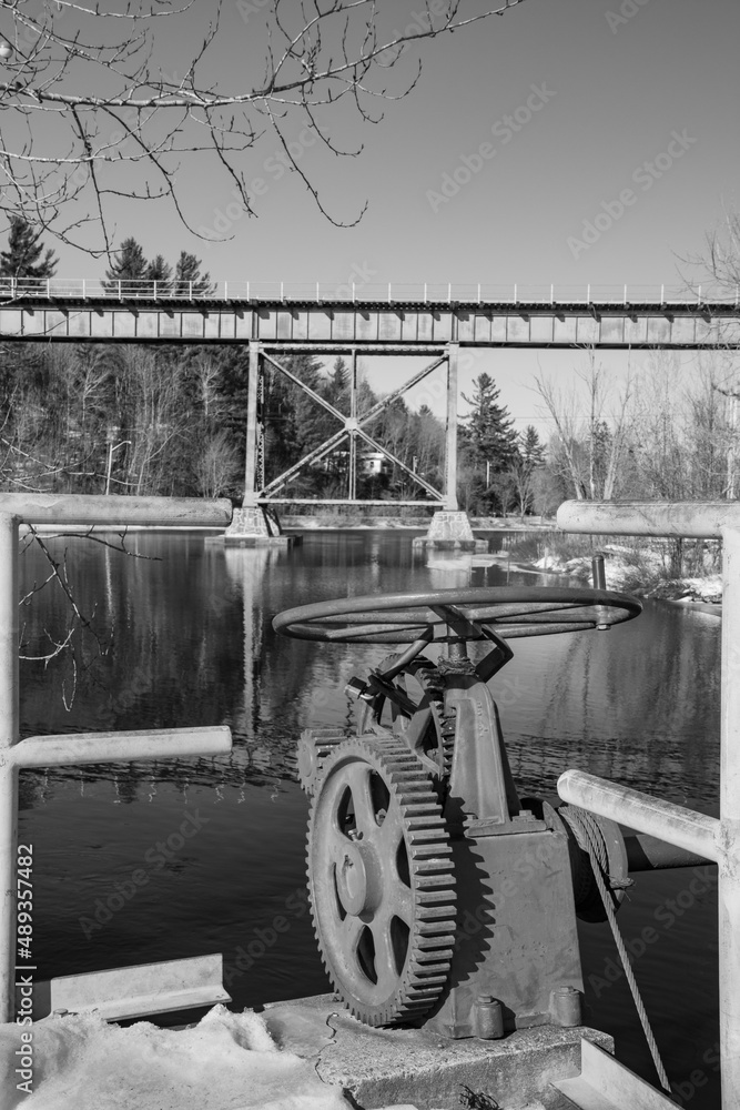 Obraz premium Dam gear and railway bridge over river in winter in Quebec, Canada