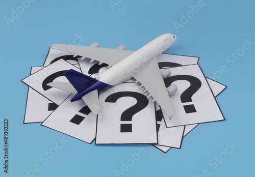 Airplane and question marks on blue background. Travel    questions concept. 