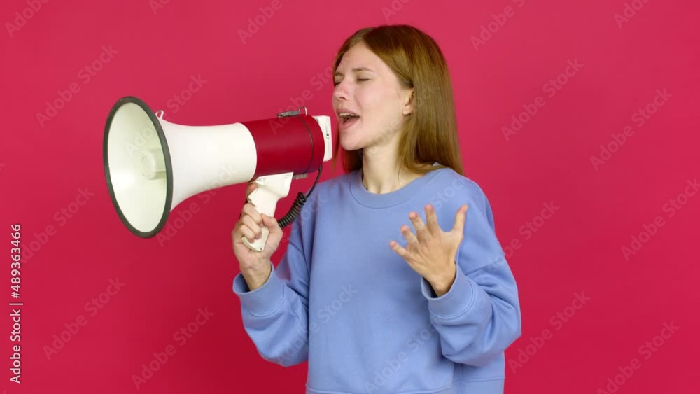 Young woman shouting through a megaphone over isolated background Young woman shouting through a megaphone over isolated background