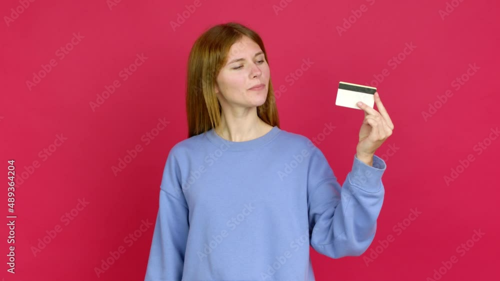 Young woman happy and holding a credit card over isolated background Young woman happy and holding a credit card over isolated background