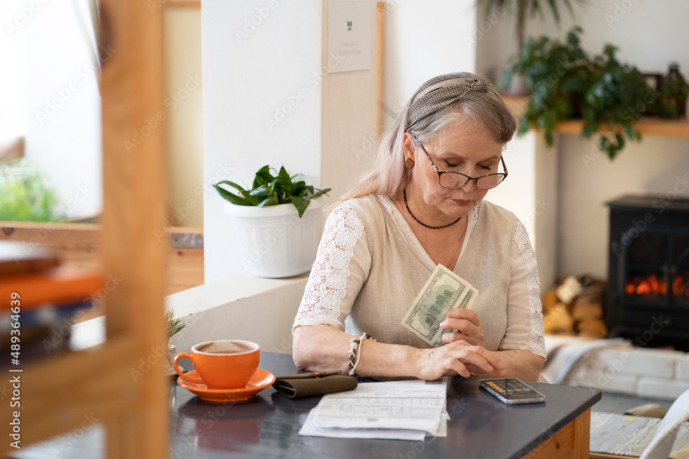 Elderly woman counts money and pays bills Elderly woman counts money and pays bills