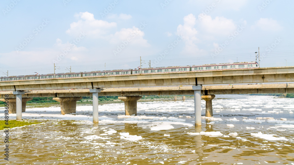 View of a newly build metro rail bridge by Delhi Metro and polluted Yamuna river
