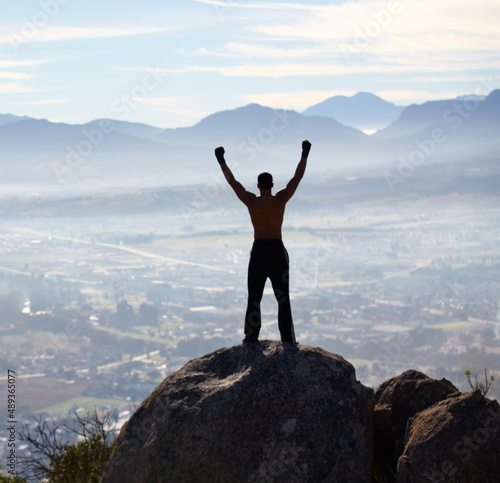 Hes reached the summit. Rearview of a man with his arms raised while standing on a mountain top.