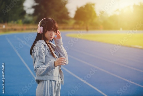 Female jogger resting while listening to mp3 music, happy young woman listening music in headphones 