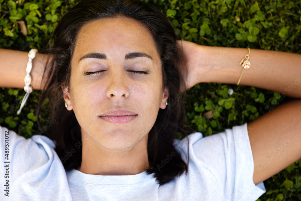 Fototapeta premium Close up from above young woman with eyes closed sleeping and hands behind head