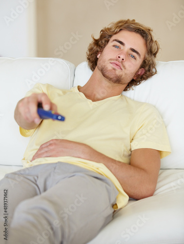 Chilling. A lazy young man flicking through TV channels. photo