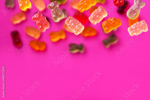 Multicolored flying gummy bears on a pink background, flat lay photo