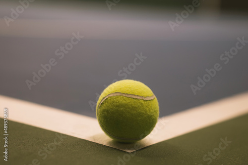 yellow tennis ball close-up on the edge of the intersection of two lines on the corner of the tennis court © Dzmitry