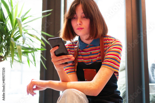 A cute bar waitress is using a smarth phone on the break. photo