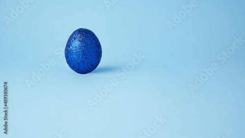 Blue glitter Easter egg.  Light blue background. Clear minimal luxury concept.  Space for text.