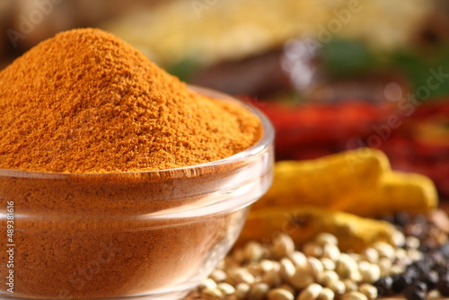 Spicy curry powder in a glass bowl along with all spice ingredients photo