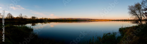 Panorama of autumn lake. Mirror reflection in water  blue sky.