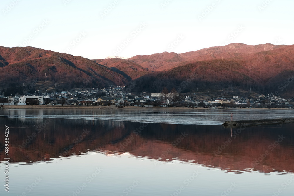 長野県下諏訪町の街並みと諏訪湖に映った山