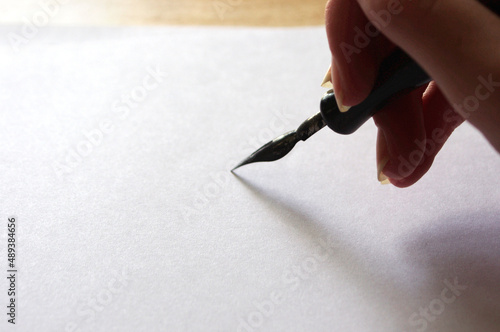 Wallpaper Mural female hand holding a black fountain pen on white paper with copy space Torontodigital.ca