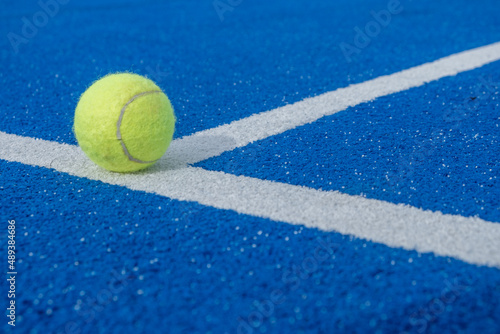 Close-up of a tennis ball on the white line of a paddle tennis court © VicVaz