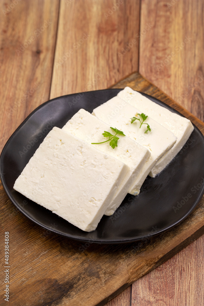 Sliced Feta cheese with herbs on wooden background. Close-up breakfast cheese