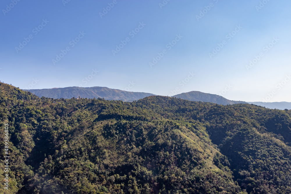 mountain range covered with green forests and misty blue sky at morning from flat angle