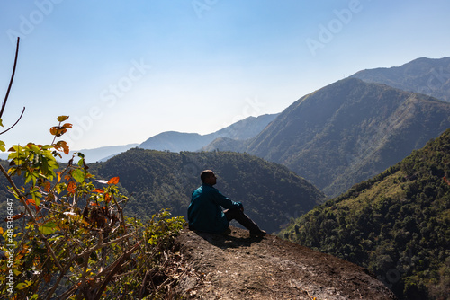 isolated young man at mountain top with green forests and misty blue sky at morning from flat angle