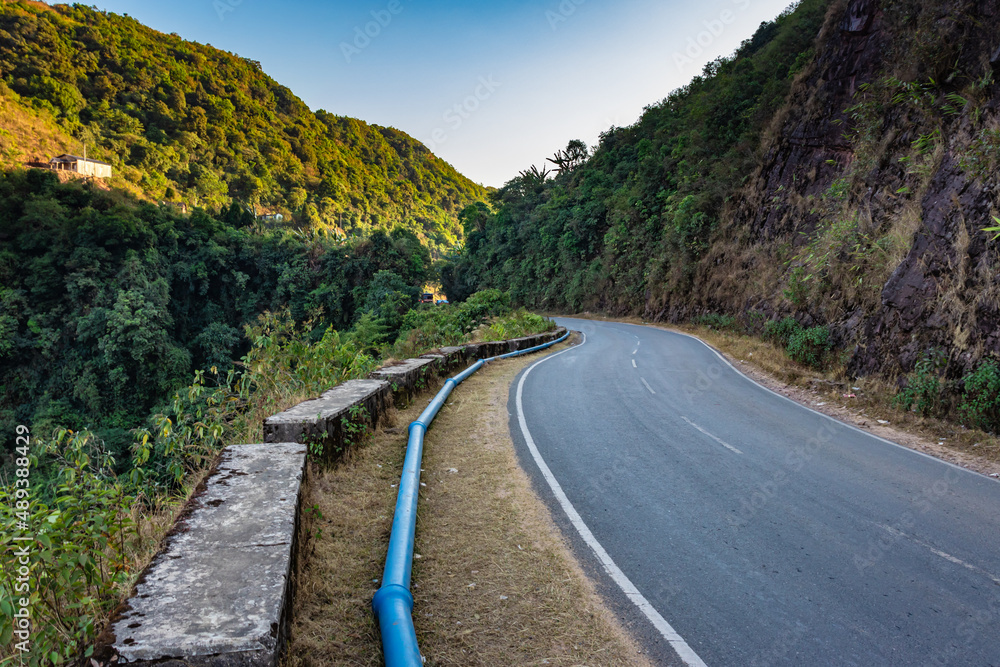 isolated mountain tarmac curvy road with bright blue sky at evening from flat angle