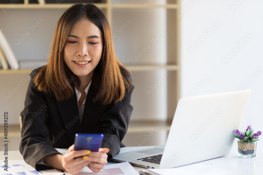 Business woman in office working with laptop using mobile phone on desk. Business woman in office working with laptop using mobile phone on desk.