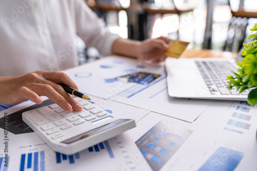 Businesswoman working at her desk using calculator to calculate earnings figures  profit  calculate monthly expenses  taxes  manage budget accounting concepts.