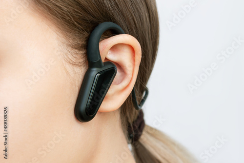 Black wireless headphones with bone conduction for sports, running, cycling on a head of a young woman listening to music isolated on a white background. Close up