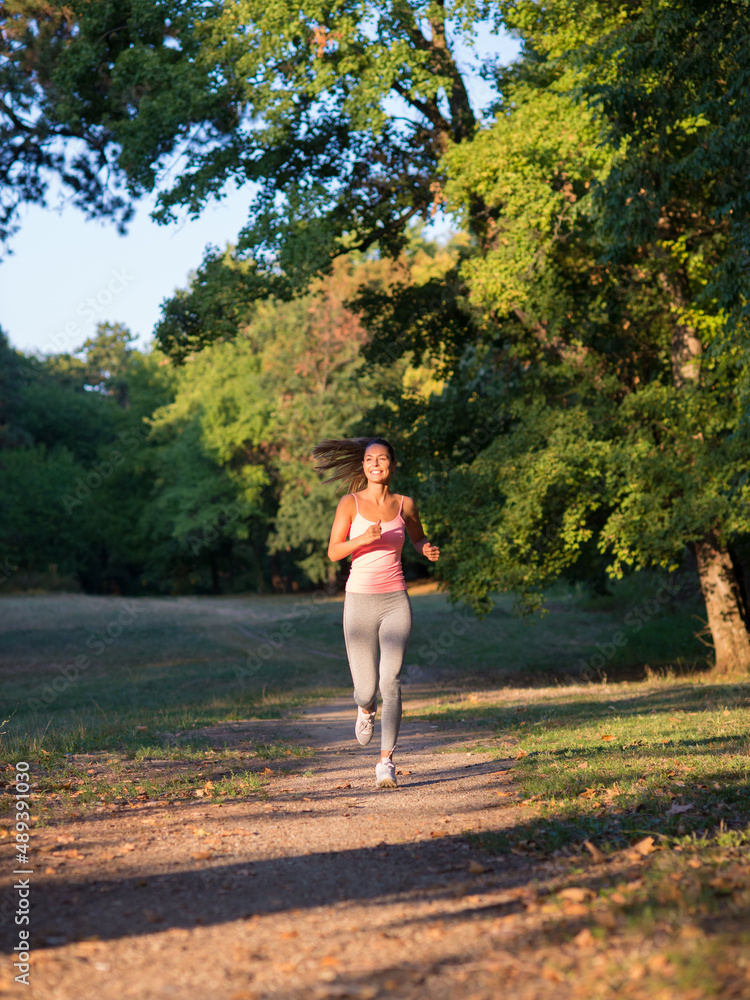 Young smiling fitness woman running and exercising in the park on a sunny summer day. Young smiling fitness woman running and exercising in the park on a sunny summer day.