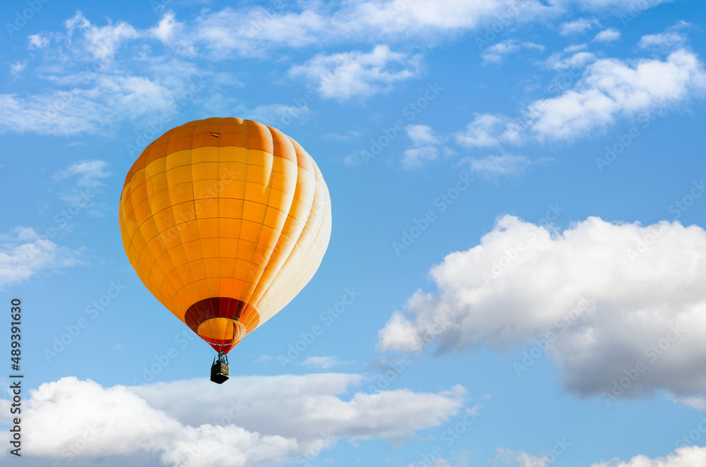 Naklejka premium Orange hot air balloon flying over blue sky