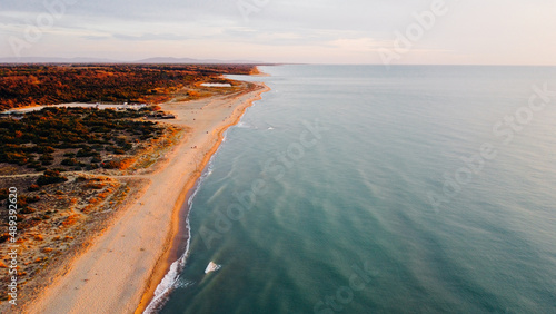 Aerial view of coastline and fall vegetation in Tuscany  Italy. Bird's eye view of sandy shore and Ligurian sea at sunset. Drone photography. © Iryna