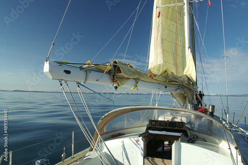 jacht z żółtym żaglem płynący po spokojnym morzu w słoneczny dzień
