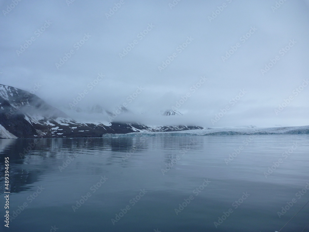 malownicze ośnieżone góry we mgle odbijające się w tafli wody w regionie svalbard na arktyce - obrazy, fototapety, plakaty 
