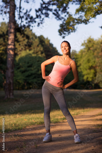 Young smiling fitness woman running and exercising in the park on a sunny summer day.
