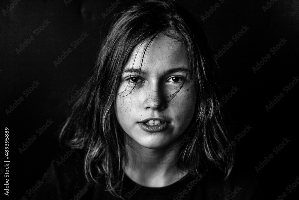 Portrait of a young girl on a black background in a low key. A serious piercing eyes. The concept of determination, strong personality, character.