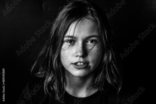 Portrait of a young girl on a black background in a low key. A serious piercing eyes. The concept of determination, strong personality, character.