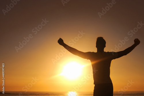 Breaking free from the rut. Silhouette of a man with his arms outstretched with the sunset in front of him.