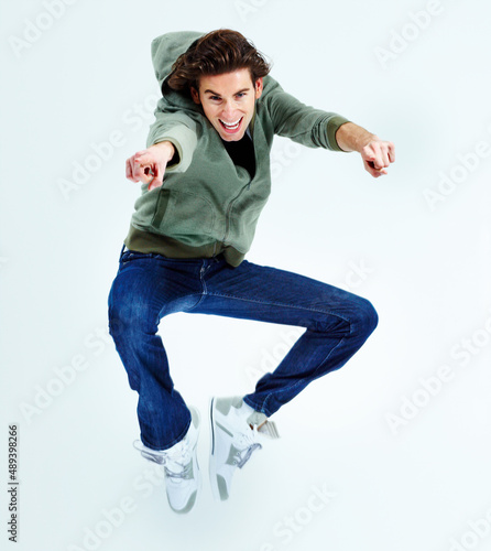 Cmon, its fun. Portrait of a young man jumping up in the air while pointing at you. photo