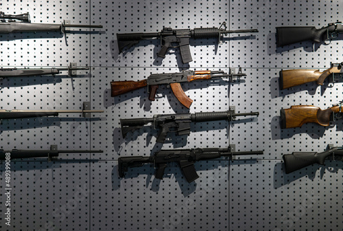 Collection of rifles and carbines. Various firearms hang on special mounts on the wall. Weapon back photo