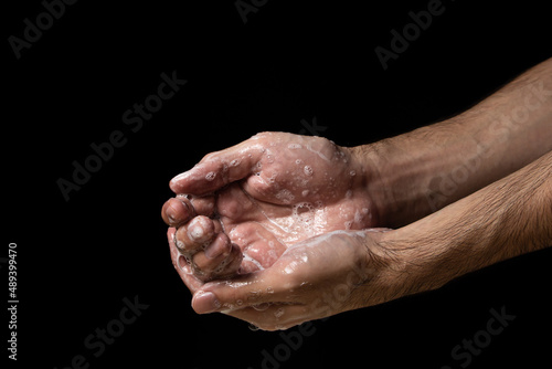 Washing hands with soap on a black background. Personal hygiene and health care.