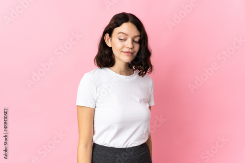 Teenager Ukrainian girl isolated on pink background making doubts gesture looking side