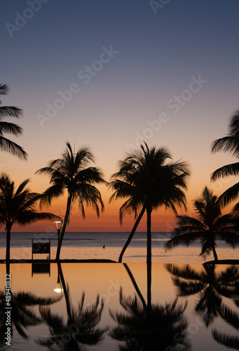 Sunset in Mauritius at Troux-aux-biches beach with palm trees, infinity pool and the sea with beautiful colors. Upright