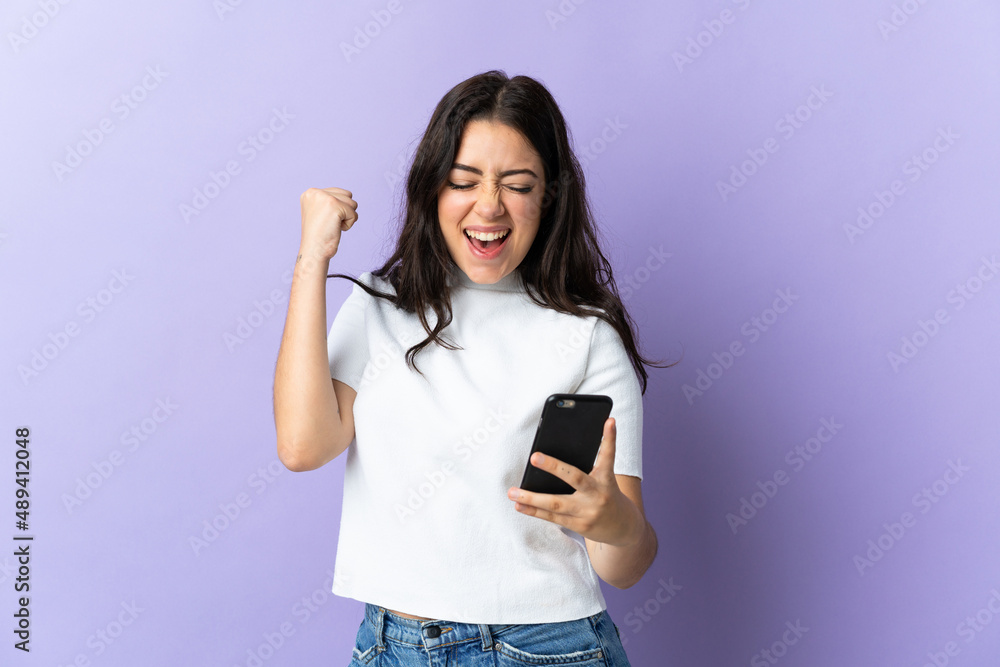 Young caucasian woman isolated on purple background with phone in victory position Young caucasian woman isolated on purple background with phone in victory position