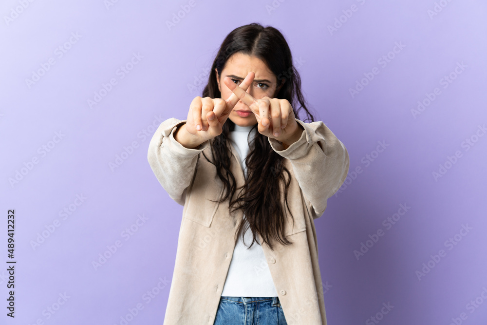Young caucasian woman isolated on purple background making stop gesture with her hand to stop an act Young caucasian woman isolated on purple background making stop gesture with her hand to stop an act