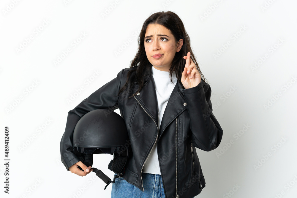 Woman holding a motorcycle helmet isolated on white background with fingers crossing and wishing the best Woman holding a motorcycle helmet isolated on white background with fingers crossing and wishing the best