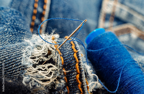 Hole in jeans. Needle with thread for darning jeans. Tools for work dressmaker, seamstress fashion designer