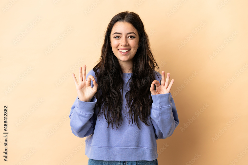 Young caucasian woman over isolated background showing ok sign with two hands