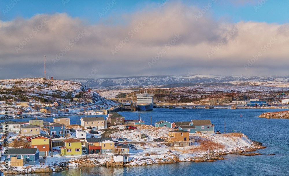 A panoramic view of Channel Port aux Basques, Newfoundland during winter. The small coastline community has snow covered colorful houses, Marine Atlantic ferry and terminal with a sheltered harbour. 